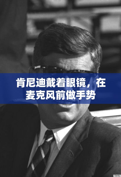肯尼迪戴着眼镜，在麦克风前做手势